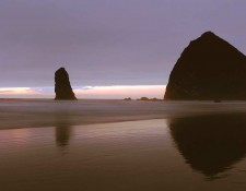 Haystack Rock, Canon Beach, Oregon. Coastal erosion is a fact of life, but many of us forget that tides and waves have a significant effect on our shores, as it often happens over long periods of time. These pillars at Cannon Beach in Oregon were no doubt once a part of the land mass that has been all but washed away by the forces of nature and time. It is now one of the great walking beaches on the West Coast, so much so, that it is lined with homes. Local residents vounteer to interpret and protect the rock during low tides for visitors during summer. The width of the beach at low tide is so vast, that you can walk to the largest of these remaining potrusions, Haystack Rock, to clearly see the hundreds of Tufted Puffins, Gulls and Cormorants perched on its rocky surface. Nature is still working on them, evident from the sea tunnel within Haystack
